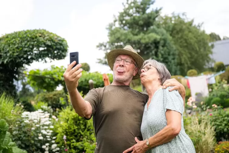 Zwei ältere Menschen nehmen im Garten ein Selfie auf